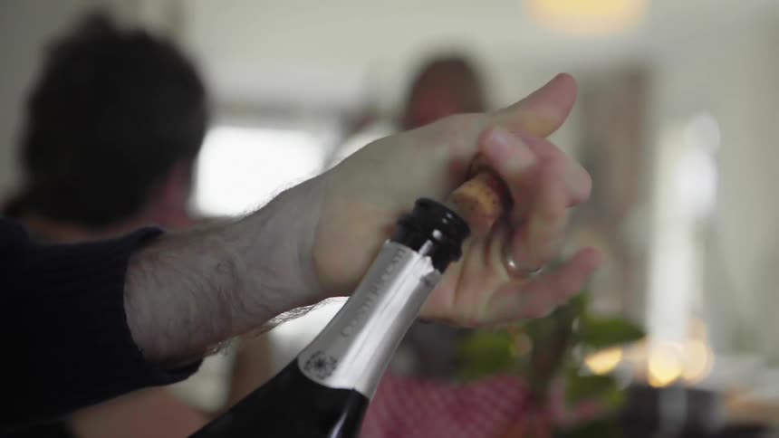 A man opens a bottle of wine at home