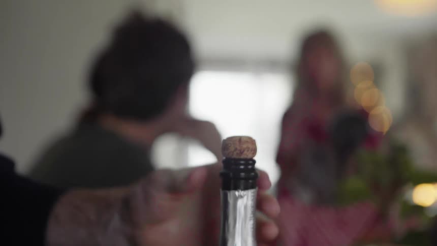 A man opens a bottle of wine at home