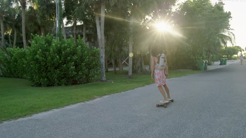 Woman rides a skateboard on the streets while carrying a dog in a backpack