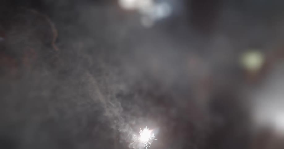 People waving sparklers outside at night