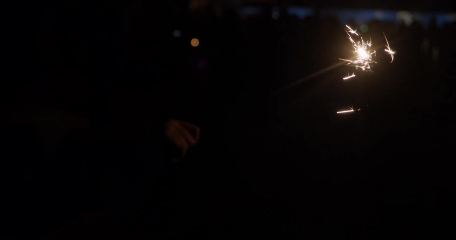 A person twirls a sparkler outdoors