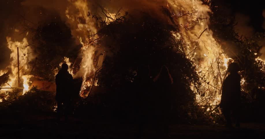 People wander around a giant bonfire