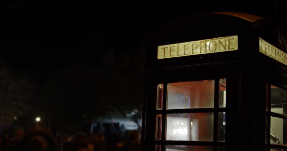 A phone booth in front of some people outside