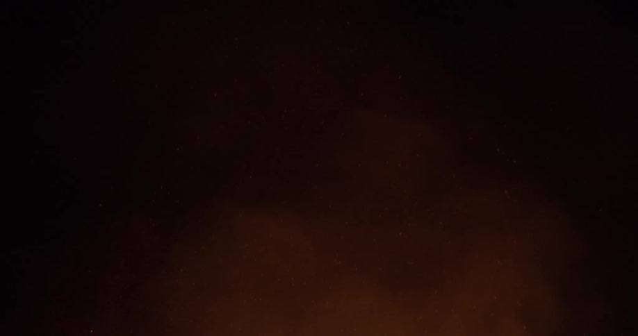 Smoke billows off a large flame at night