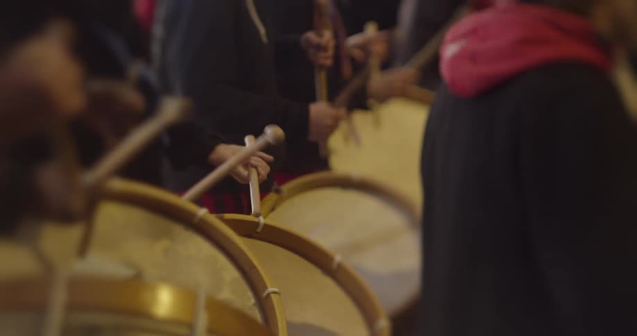 People beating on drums with drumsticks