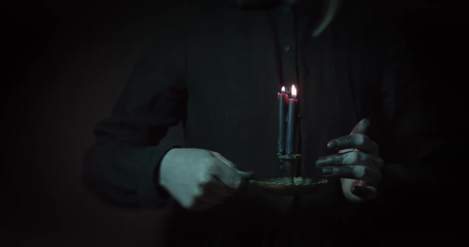 Woman wearing black shirt holds candles in a dimly lit room