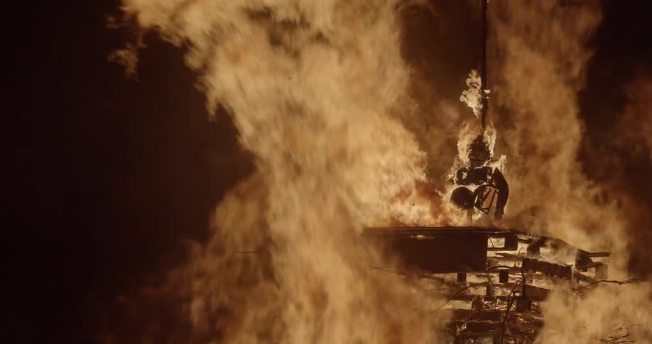 A human shaped figure burns on top of a giant bonfire