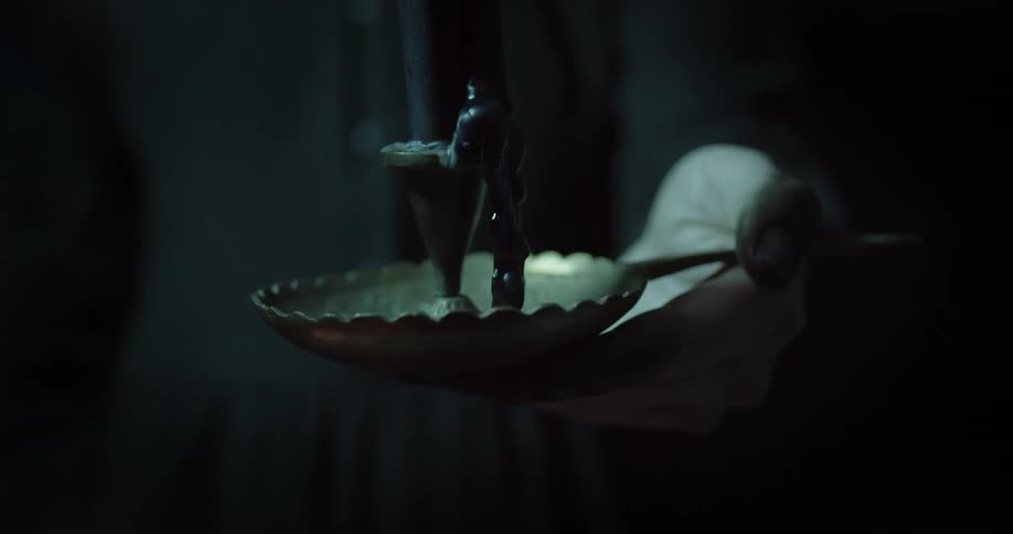 A person holds a dripping candle