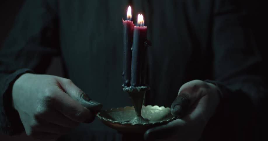 A person holds a candlestick holder with two burning candles in it