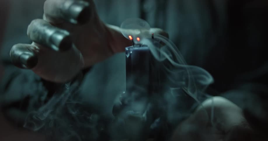 Hand gets close to the burning wicks on the candles as smoke emits from them