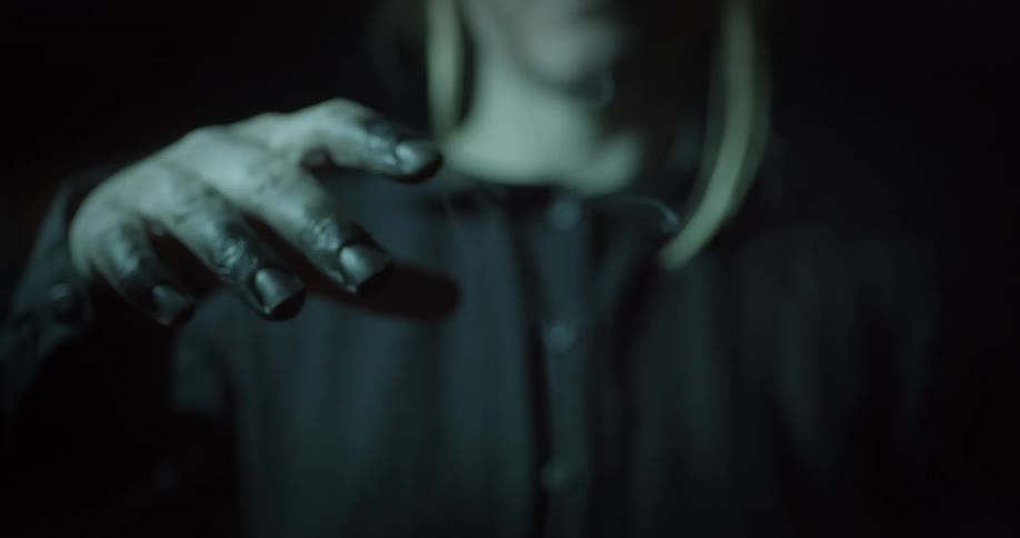 A person waving their hand with smoke rising up in front of them