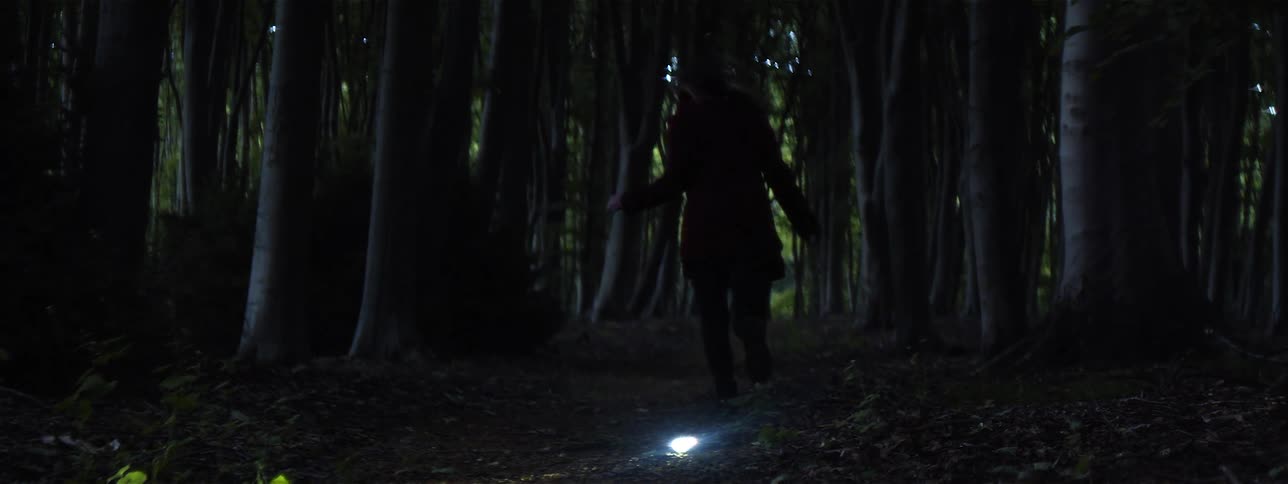 Female stops on hiking trail as a glowing object startles her when it flashes brightly and she begins to run away in fear