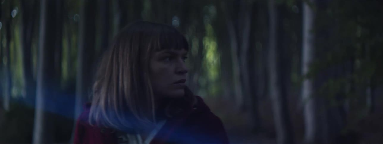 Woman stands in the dark forest