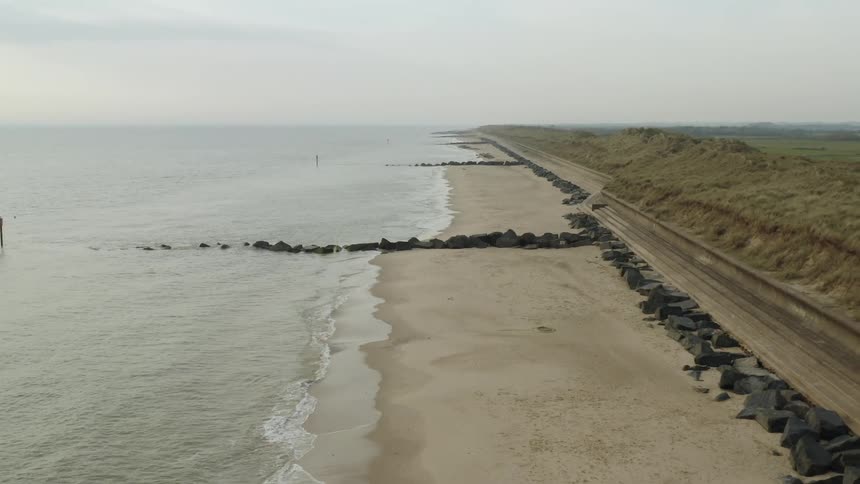 Aerial view of calm waves crashing on the sands of a beach