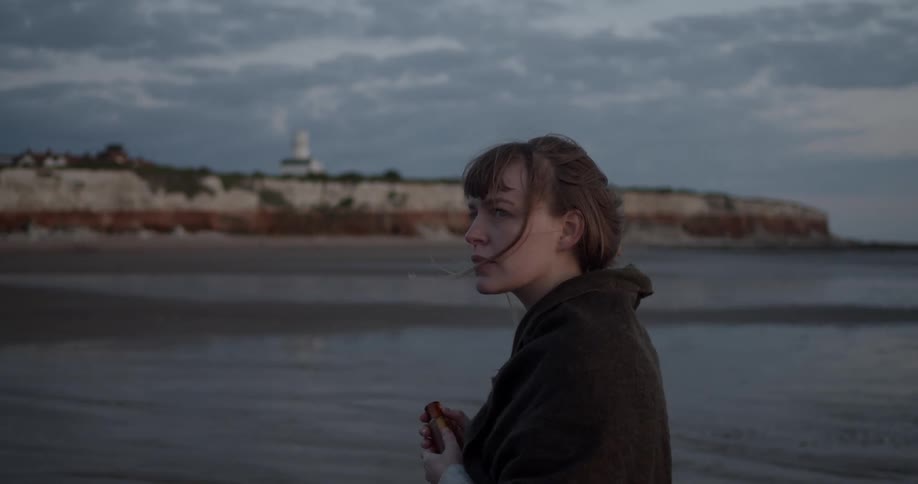 A young woman walks along the shore