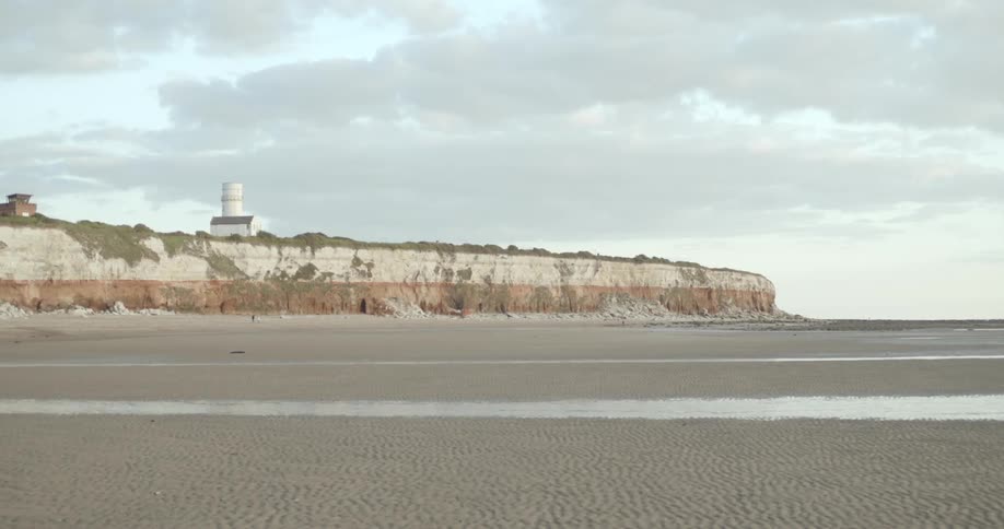 The lighthouse is near the cliff in the distance