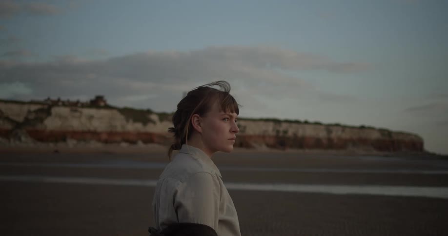 A woman stands on the beach looking at the ocean