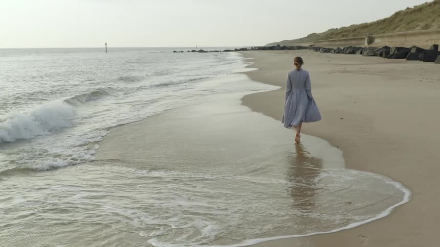 Woman walking along the shoreline on the coast