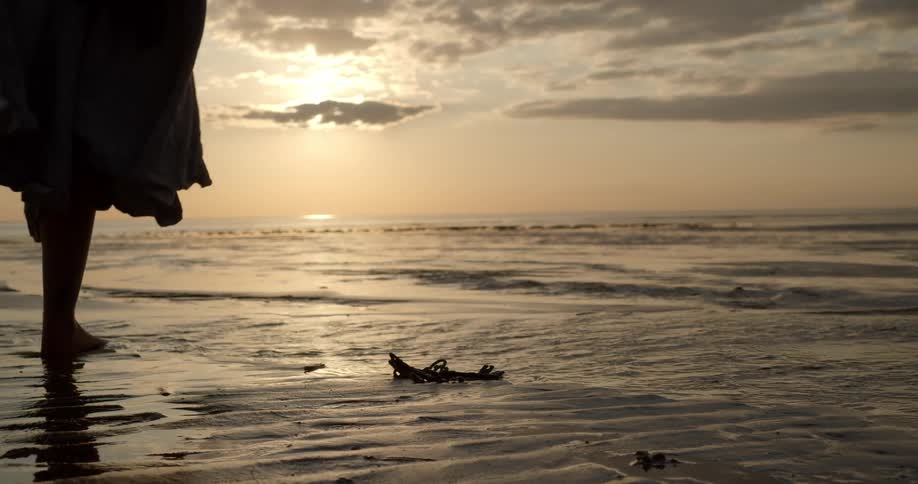 A woman walking on the beach with old keys in the foreground