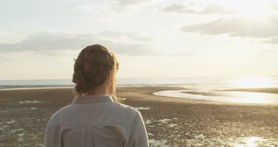 A young woman walks along the beach