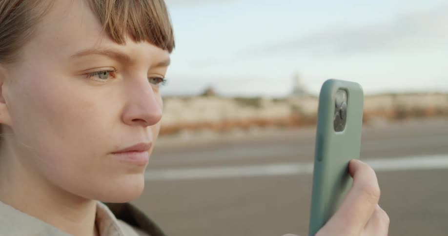 A woman on the beach looks at her phone