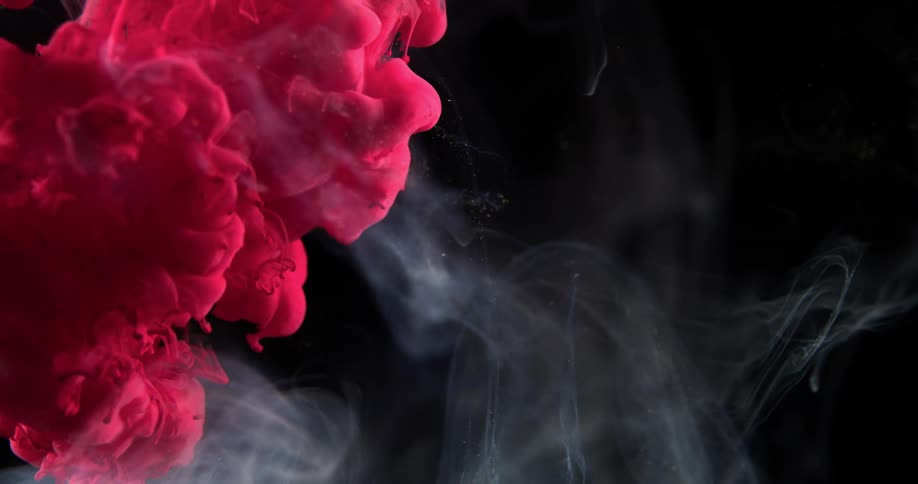 A pink fluid billows into a solution with a smoky appearance