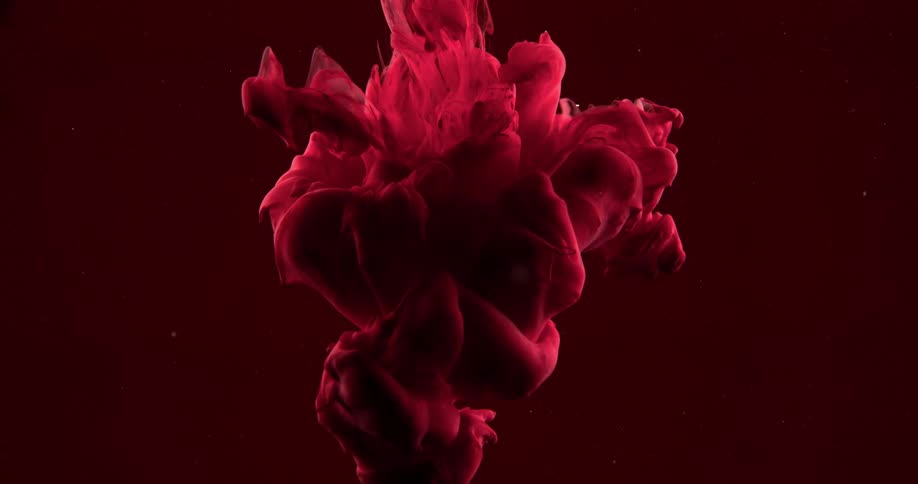 Red mass flows and expands in liquid sending up bubbles