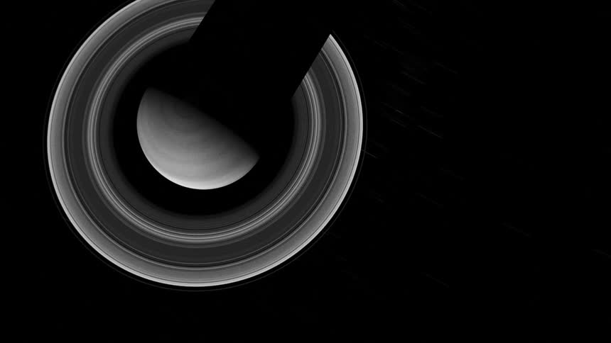 Ball spins on arm over rotating concentric circles in shades of gray white and black