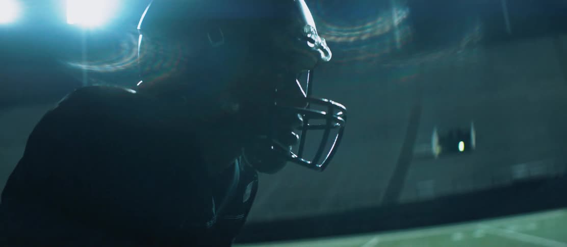 Football player stands in a footbal field in a stadium at night