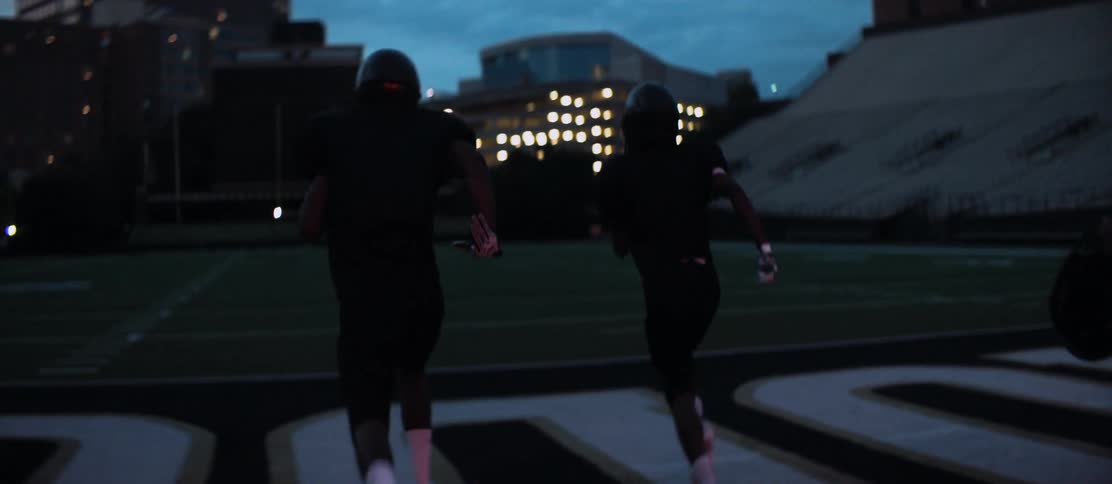 Three football players running on to a field