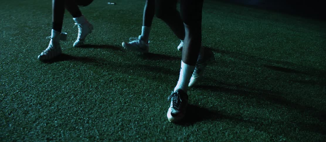 Three black football players walk across the field
