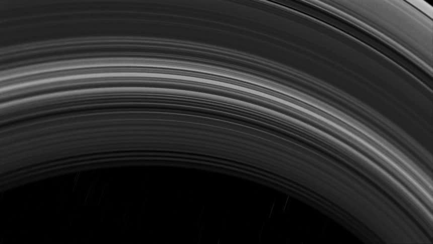Stars move across the sky behind the rings of saturn