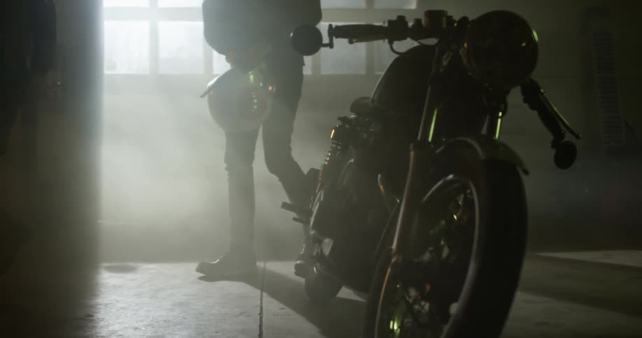 Two men walk in to a room and look at a motorcycle