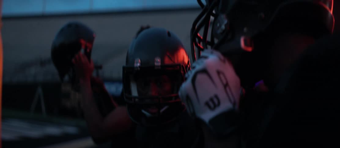 American football players celebrate in a stadium at night