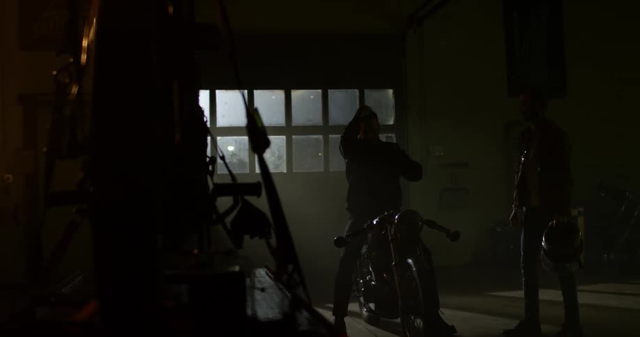 A man sitting on his motorcycle puts on his helmet