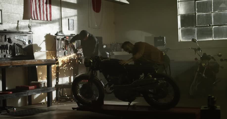 Two mechanics work on a motorcycle in a garage