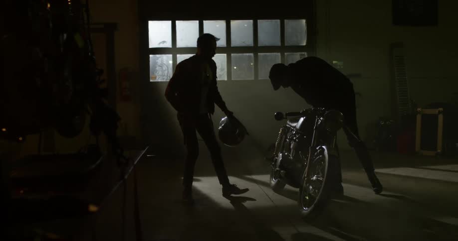 Two men in a garage working on a motorcycle