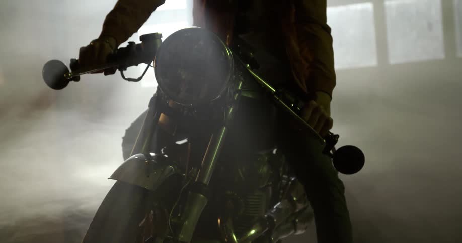 A white man sits on a motorcycle inside a building