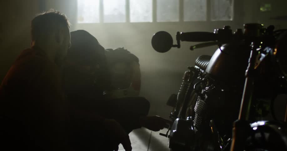 Two men check out a motorcycle in the garage