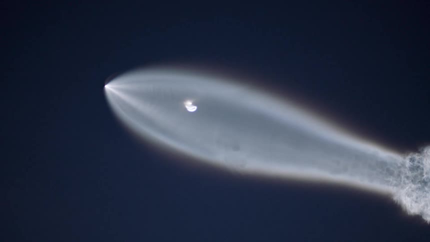 A rocket sails through the sky leaving a wide tail behind it