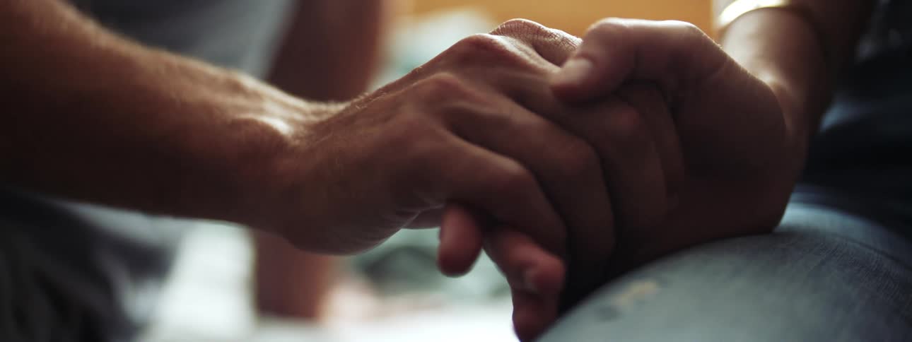 A man and a woman slowly hold hands