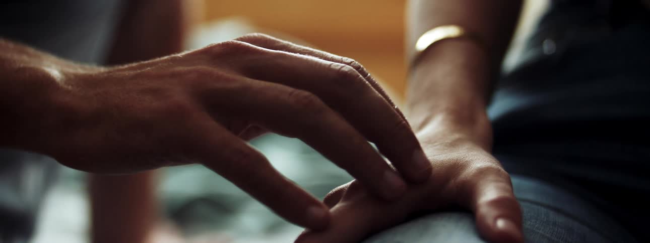 A white man caresses a white womans hand and arm