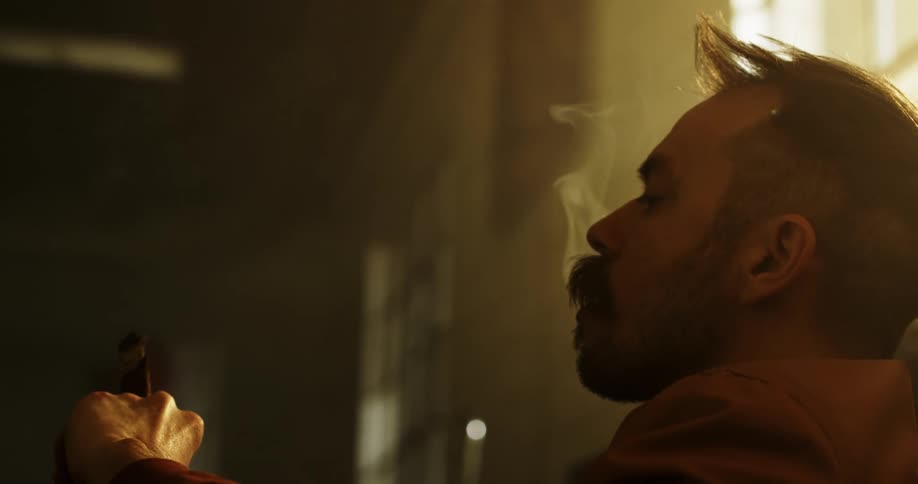 A white man sits inside a building smoking a cigar