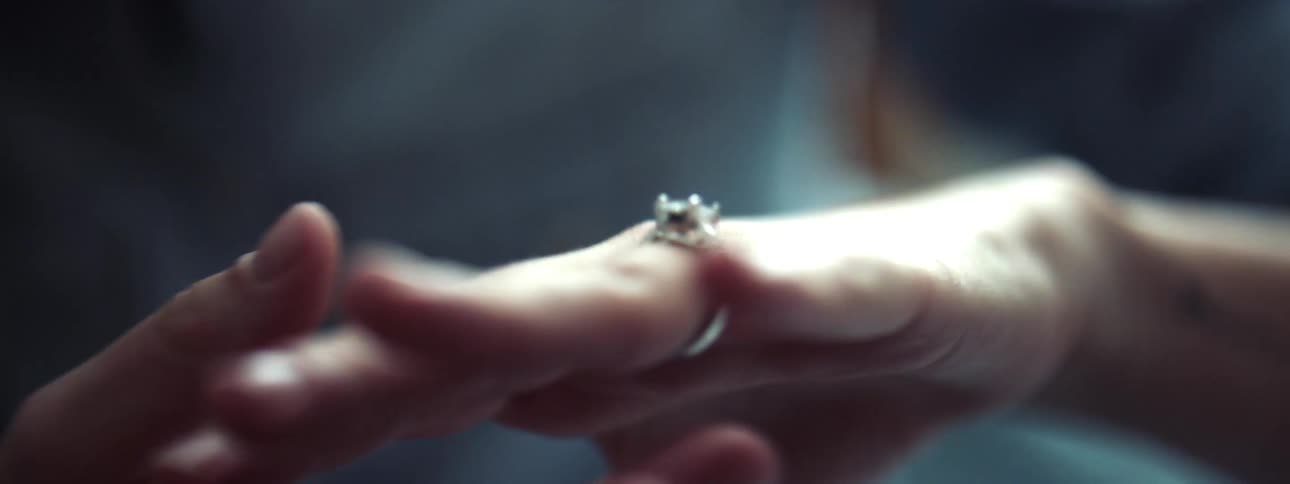A woman looking at and touching a ring on her hand
