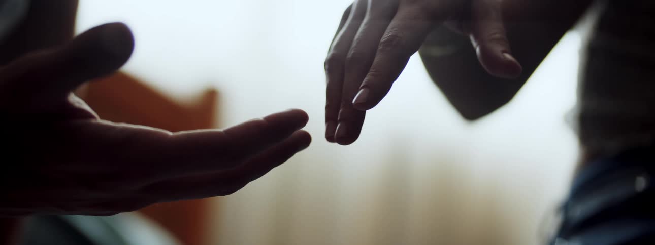 A man and woman caress and touch hands and finger tips in a romantic fashion