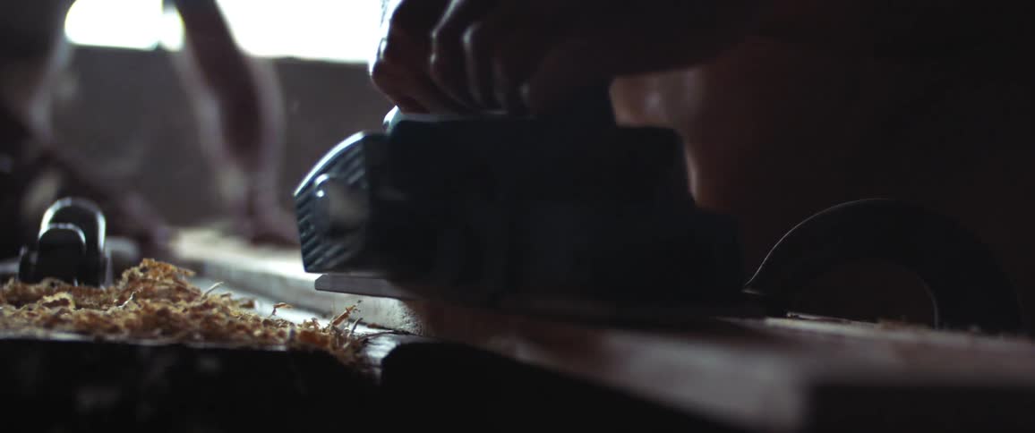 A person is sanding a plank of wood