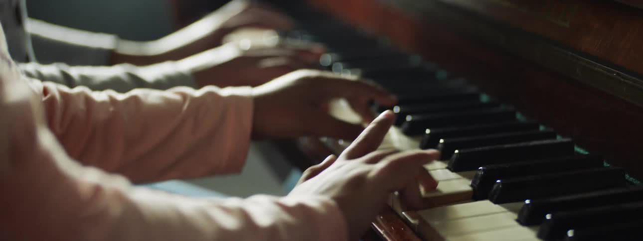 A man and a woman sit at a piano and play