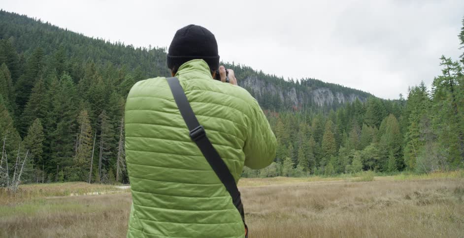 A young man takes pictures of a forest