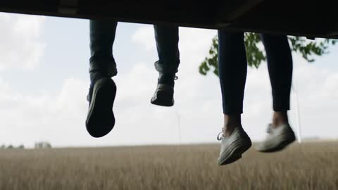 Two people kick their feet by the field