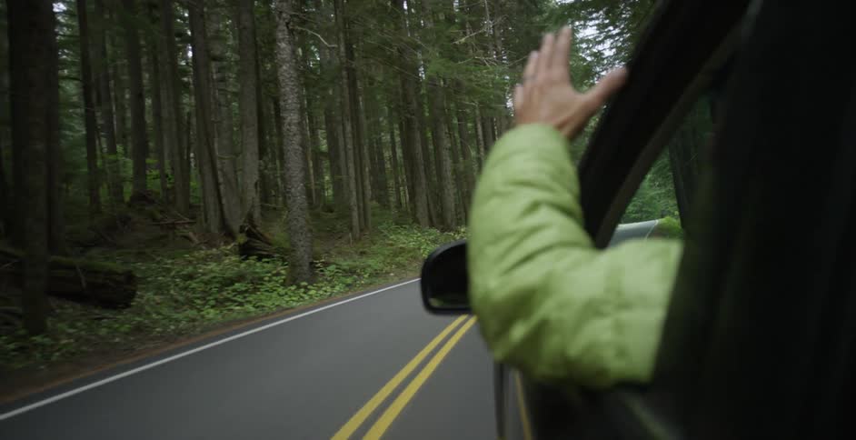 A man hangs his arm out the window as he drives